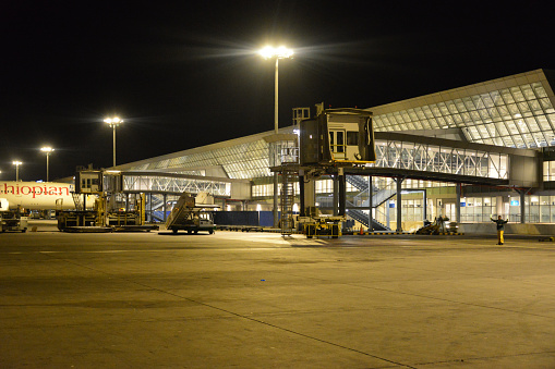 Addis Ababa, Ethiopia: air-side view of Terminal 2 at night - passenger boarding bridges and aircraft marshaller at Addis Ababa Bole International Airport (IATA: ADD, ICAO: HAAB).