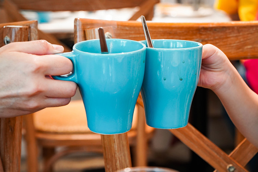 Mom holding a child's blue coffee cup and chocolate mug