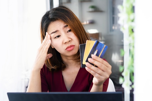 sad Asian woman having problem with debt ,over spending money from shopping hand holding credit card and worry about late , deadline payment