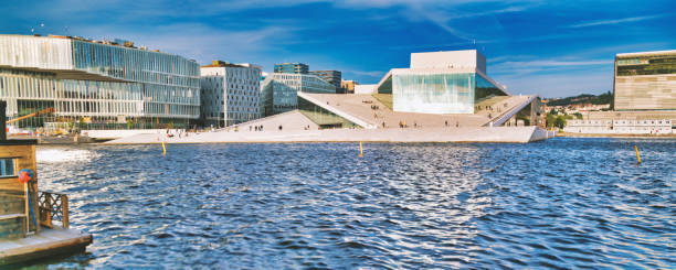 Panoramic view of the modern Opera House of Oslo, Norway. In 1999, after a long national debate, the Norwegian legislature decided to construct a new opera house in the city. In 2008 it was opened y His Majesty King Harald, Queen Margrethe II of Denmark. Until today more than a million visitors every year since then visit this famous landmark of norway. The angled exterior surfaces of the building are covered with marble from Carrara, Italy and white granite and make it appear to rise from the water. It is the largest cultural building constructed in Norway.