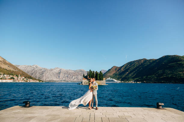 istock Full Length Of Couple Embracing While Standing Against Lake 1320938325