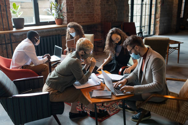 istock Business people in masks working by tables in office 1320939564