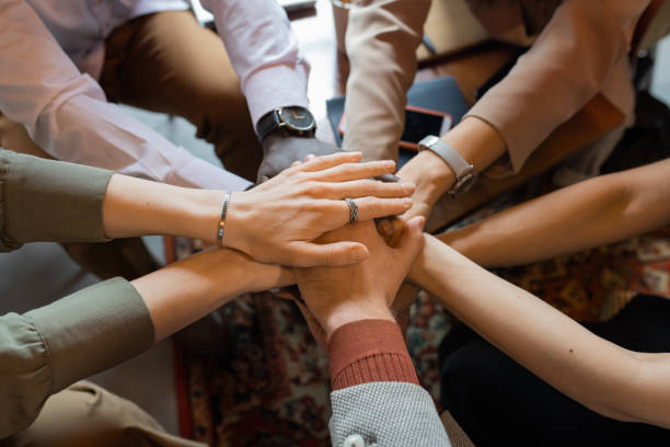 Pile of hands of several intercultural colleagues Pile of hands of several intercultural colleagues symbolizing teamwork and support hands clasped stock pictures, royalty-free photos & images