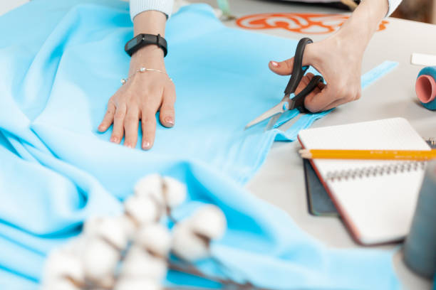 istock Scissors cut the fabric. Seamstress at work, individual tailoring 1320939880