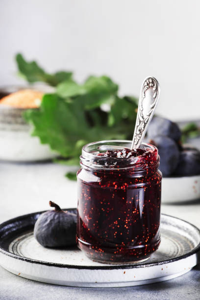 Sweet Red Fig Jam Jar. Fresh blue figs. Homemade preparations and canning. Gray table background, copy space