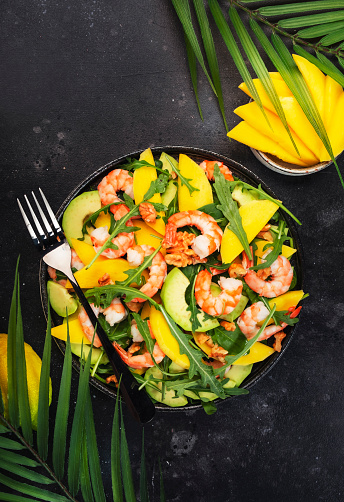 Fresh Shrimps, Mango and Avocado Salad with Walnut, Spinach and Arugula. Top view, gray table