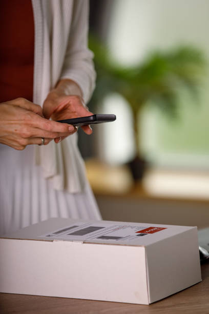 istock Woman using smart phone and taking a photo of labeled package 1320946021