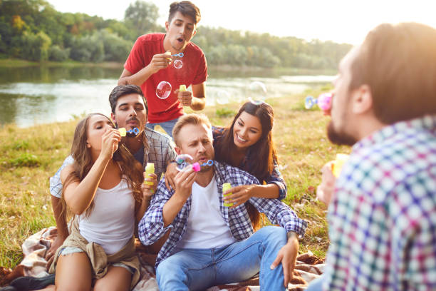 istock Young people make soap bubbles while sitting on the grass on in nature. 1320946113