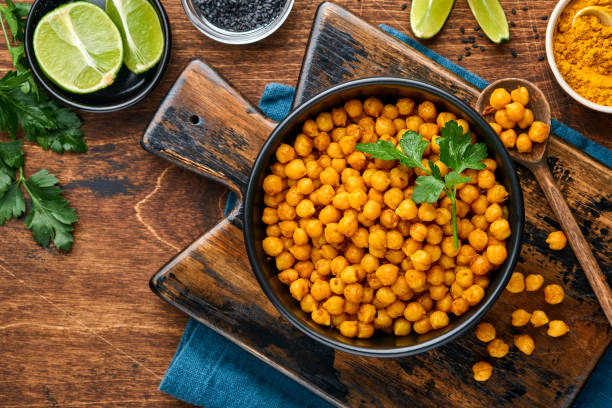 istock Fried chickpeas with turmeric in ceramic plate on an old wooden table background. Roasted spicy chickpeas or Indian chana or chole, popular snack recipe. Top view. 1320946247