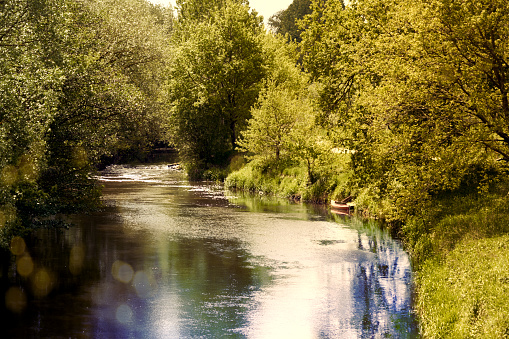 The small river Aller near Gifhorn in Germany in bright sunlight with a canoe for a boat trip, backlight with sun flare