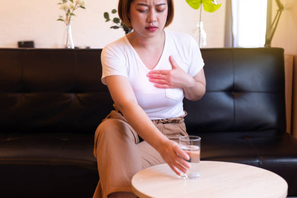 donna asiatica con o acidi sintomatici da reflusso, malattia da reflusso gastroesofageo, acqua potabile - esofago foto e immagini stock