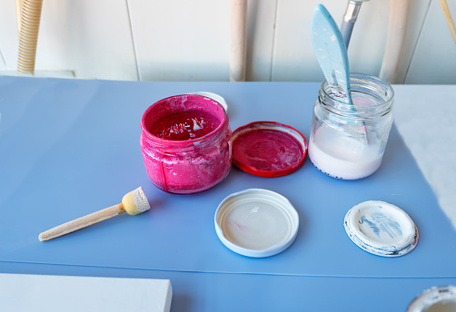 two wooden paint brushes and several cans with colored paint to make decorating crafts at home. HOuse