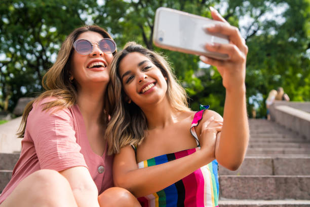 istock Two friends taking selfie with phone outdoors. 1320947687