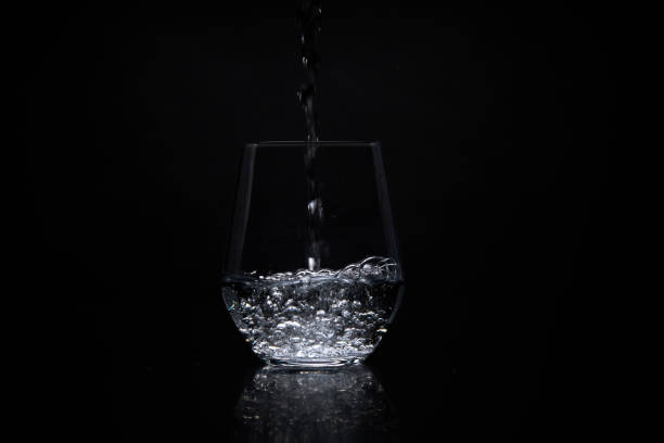 istock pouring water in a clear glass on a black background 1320947931