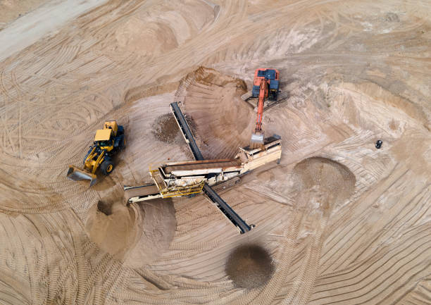 istock Arial view of the sand open-pit mining with heavy mining machinery. Mobile stone jaw crusher machine in open pit mine. Wheel loader and dump truck in opencast. Exavator on earthworks in quarry. 1320948802