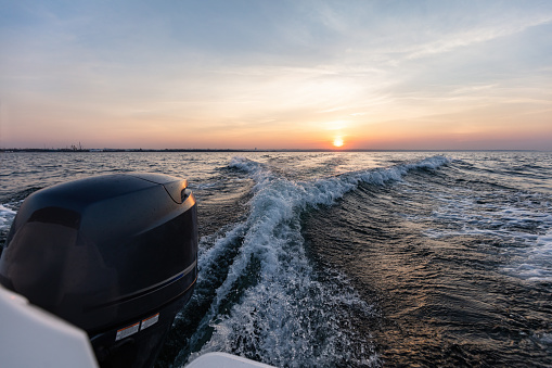 Fast motorboat ride on sea at sunset. Wake pattern behind