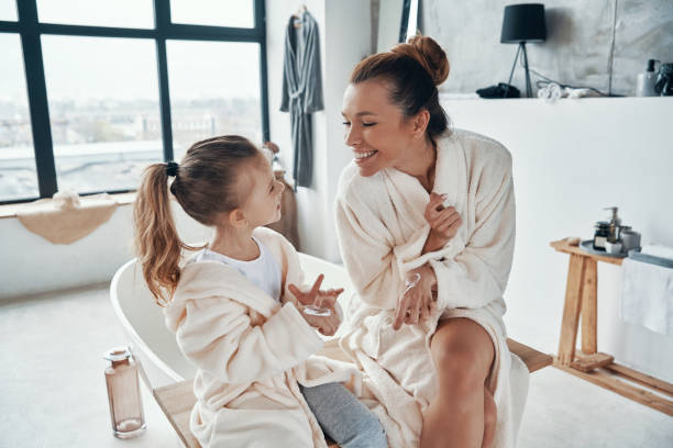 istock Mother with daughter in bathrobes smiling and using hand cream 1320950619