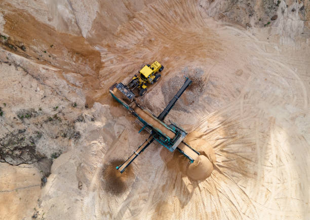 istock Arial view of the sand open-pit mining with heavy mining machinery. Mobile stone jaw crusher machine in open pit mine. 1320953627