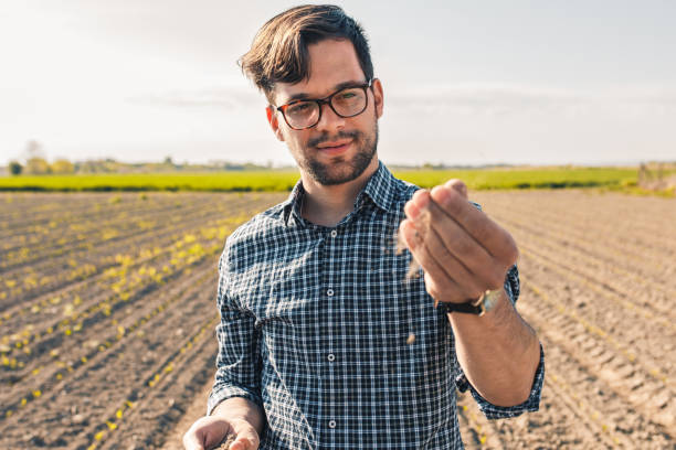 istock Young farmer in corn field examining soil quality. 1320956035