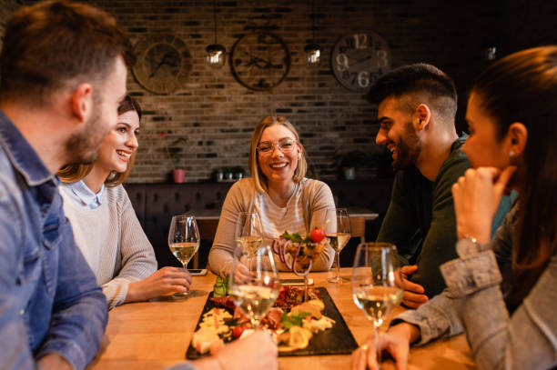 istock Group of young friends having fun in restaurant, talking and laughing while dining at table. 1320957915