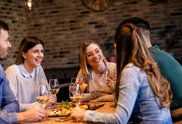 istock Group of young friends having fun in restaurant, talking and laughing while dining at table. 1320957920