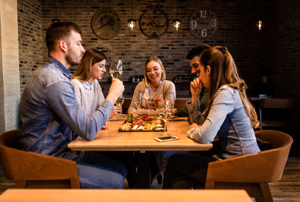 istock Group of young friends having fun in restaurant, talking and laughing while dining at table. 1320958010