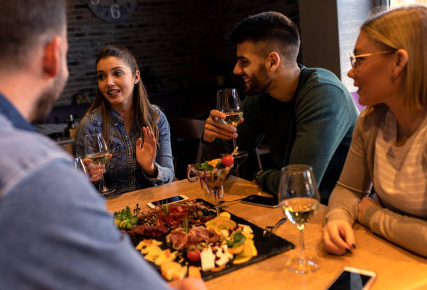 istock Group of young friends having fun in restaurant, talking and laughing while dining at table. 1320958082