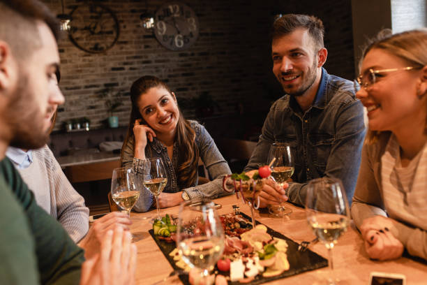 istock Group of young friends having fun in restaurant, talking and laughing while dining at table. 1320958136