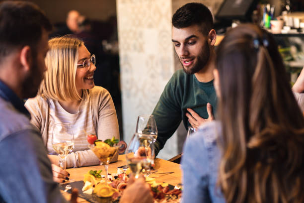 istock Group of young friends having fun in restaurant, talking and laughing while dining at table. 1320958191