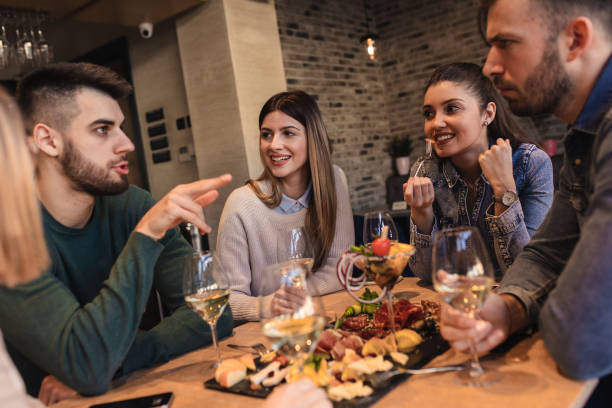 istock Group of young friends having fun in restaurant, talking and laughing while dining at table. 1320958213