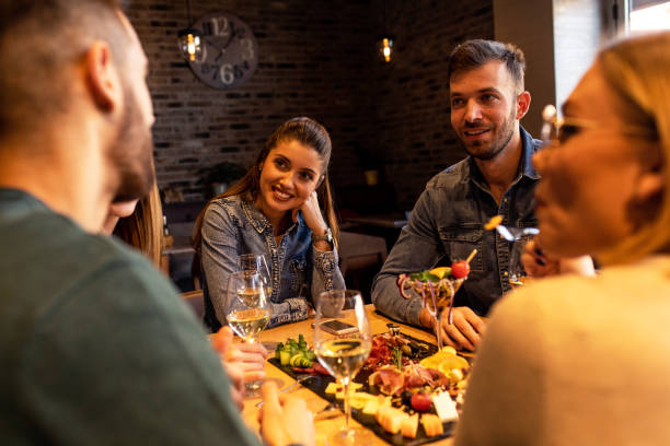 istock Group of young friends having fun in restaurant, talking and laughing while dining at table. 1320958229