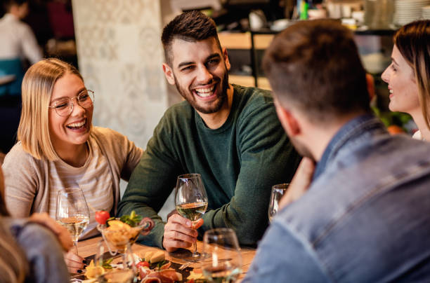 istock Group of young friends having fun in restaurant, talking and laughing while dining at table. 1320958345
