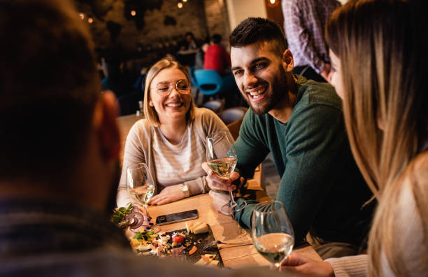 istock Group of young friends having fun in restaurant, talking and laughing while dining at table. 1320958360