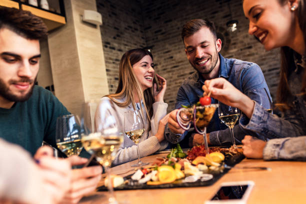 istock Group of young friends having fun in restaurant, talking and laughing while dining at table. 1320958364