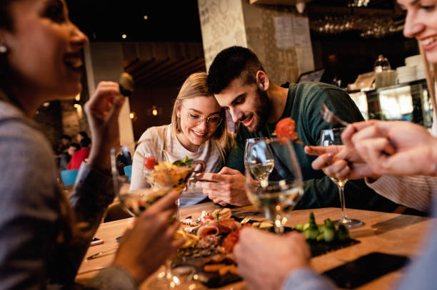 istock Group of young friends having fun in restaurant, talking and laughing while dining at table. 1320958396