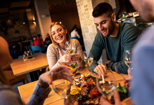 istock Group of young friends having fun in restaurant, talking and laughing while dining at table. 1320958417