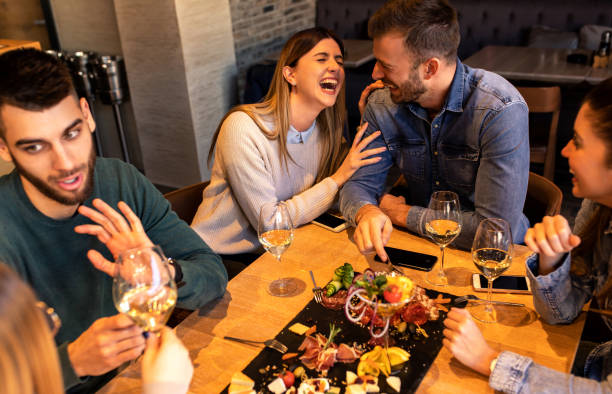 istock Group of young friends having fun in restaurant, talking and laughing while dining at table. 1320958420