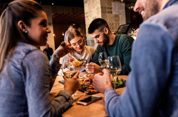 istock Group of young friends having fun in restaurant, talking and laughing while dining at table. 1320958455