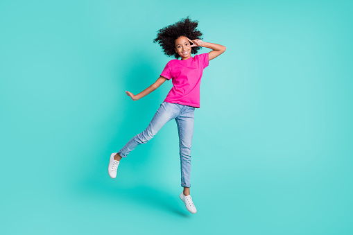 Full size photo of young pretty sweet charming lovely happy girl jump show v-sign on eye isolated on teal color background.