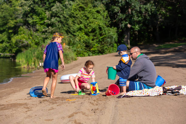 istock Father & Three Young Children Playing at Beach 1320959766