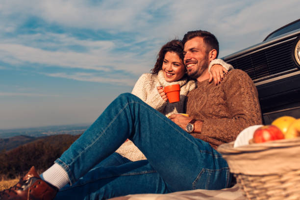 hermosa pareja joven disfrutando de tiempo de picnic en la puesta de sol - heterosexual couple fotografías e imágenes de stock