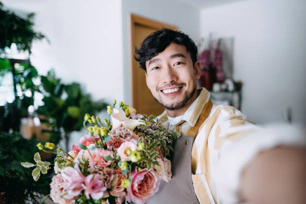 личная перспектива улыбаясь молодой азиатский ботаник мужского пола, владелец малого бизнеса цветочный магазин, делать онлайн учебник по � - florist flower arranging male стоковые фото и изображения