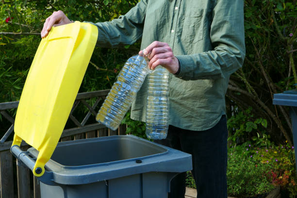 One person making a selective sorting of waste. Man putting plastic bottles in a yellow bin for recycling. bin stock pictures, royalty-free photos & images