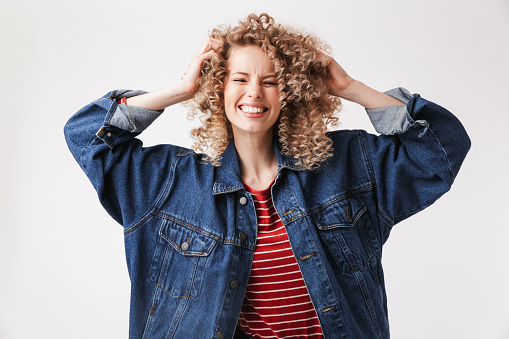 Portrait of a cheerful young girl in denim jacket posing and looking at camera isolated over white background
