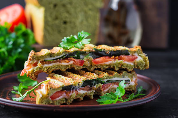 istock Vegetarian sandwich panini with spinach leaves, tomatoes and cheese on a dark table. Toast with cheese. 1320965565