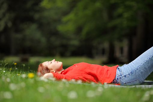 Woman resting lying on the grass in a park or forest