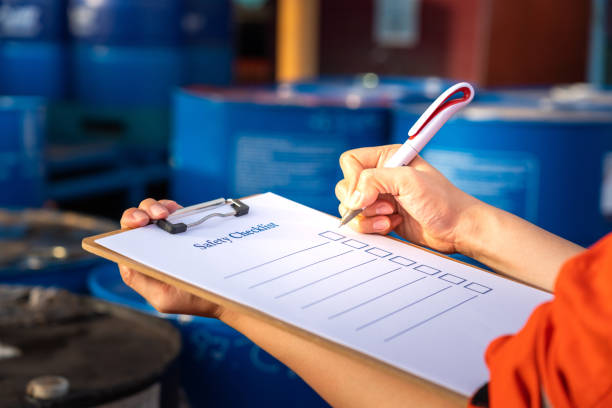 Safety inspection on the checklist document - Industrial safety concept photo. Safety inspection on the checklist document action with blurred background of chemical storage area at factory. Industrial safety concept photo. Selective focus at human's hand part. health and safety stock pictures, royalty-free photos & images