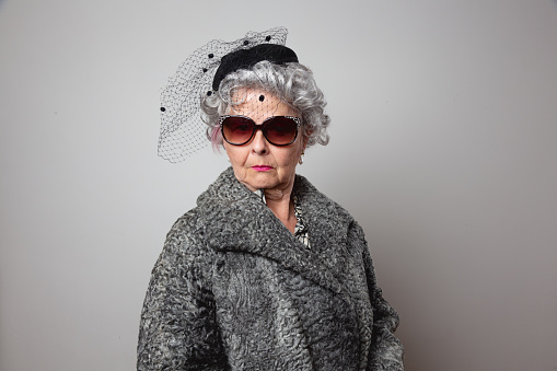 Weird senior woman wearung fur coat, sunglasses and hat