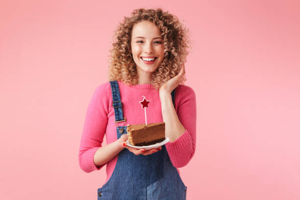 Portrait of happy young girl with curly hair Portrait of happy young girl with curly hair holding cupcake on a plate isolated over pink background woman birthday cake stock pictures, royalty-free photos & images