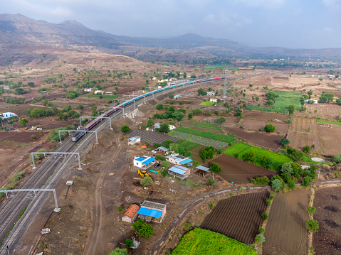 Aerial footage of a passenger train hauled by a diesel locomotive at Shindawane near Pune India.